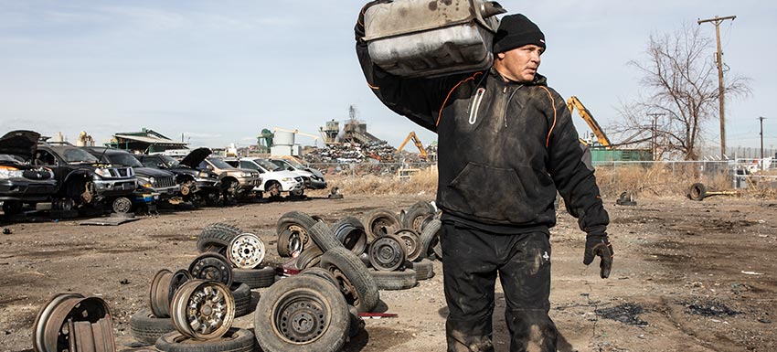 Man wearing an insulated hoodie sweatshirt carries metal for recycling.